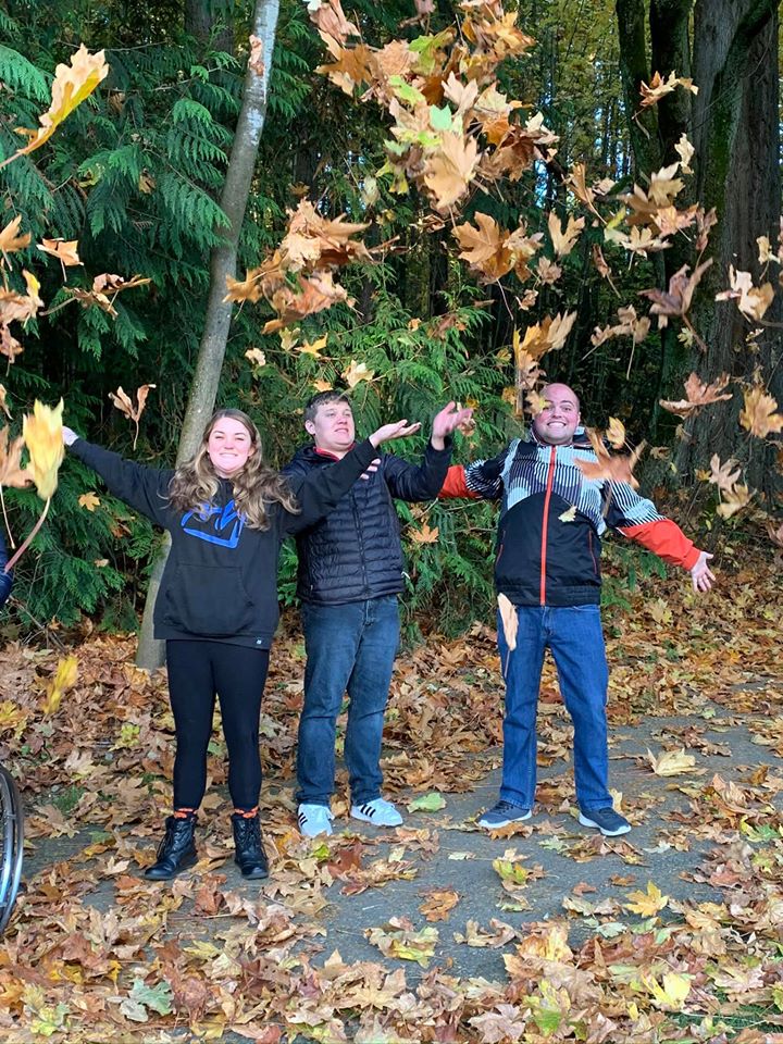 Three people standing in a pile of leaves.