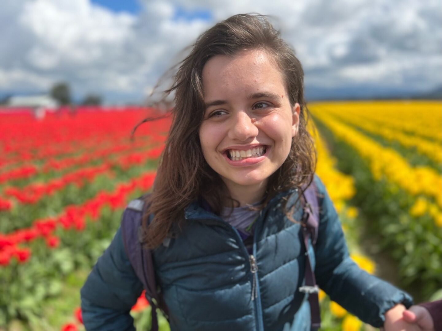 A woman standing in front of a field with flowers.