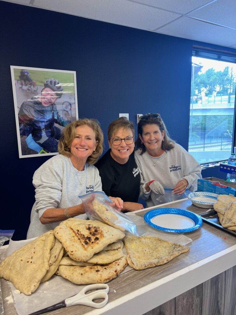 Three women are making pita bread sandwiches.