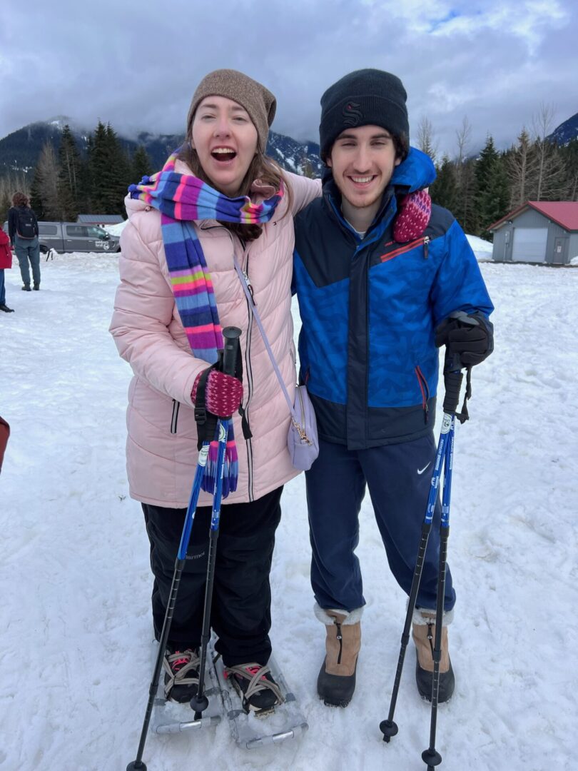 Two people standing in the snow with skis on.